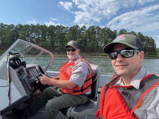 Two rangers wearing life vests sitting in a boat